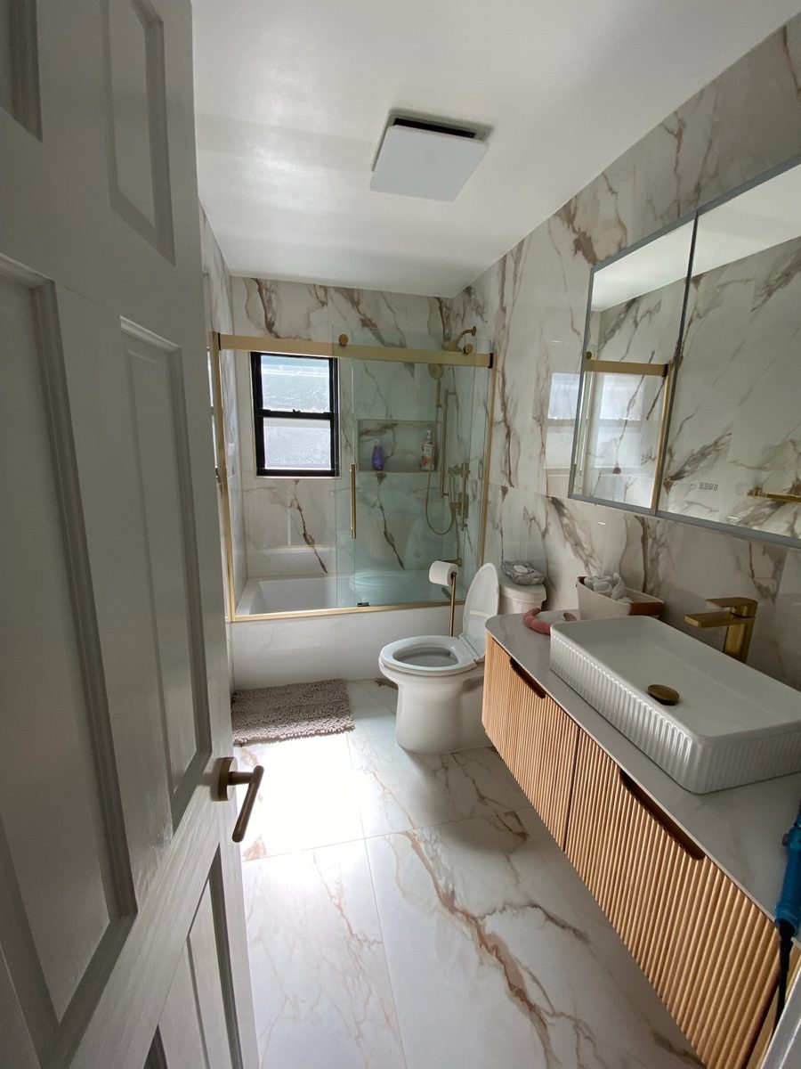 After: marble-look tile, floating wood vanity and glass tub enclosure