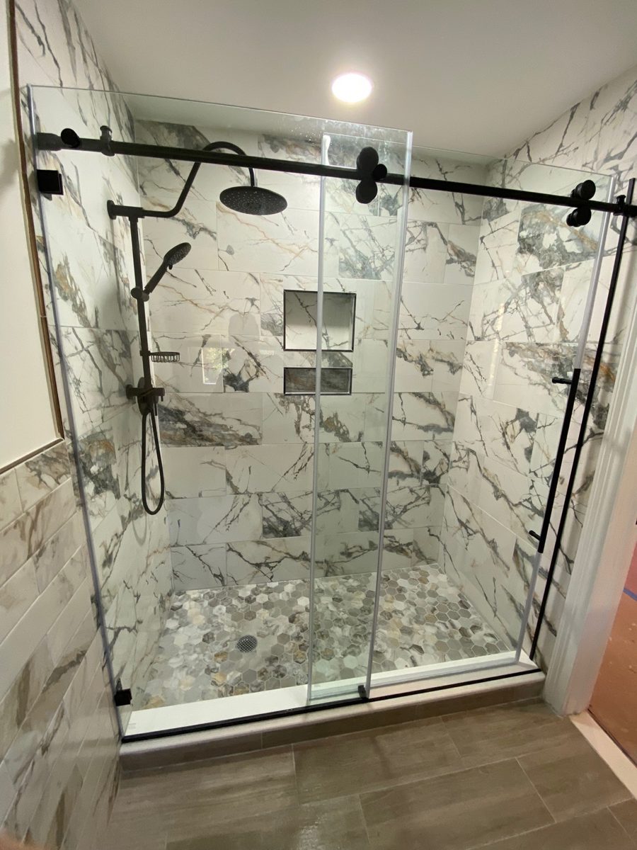 Finished walk-in shower with marble-look tile and a sliding glass door