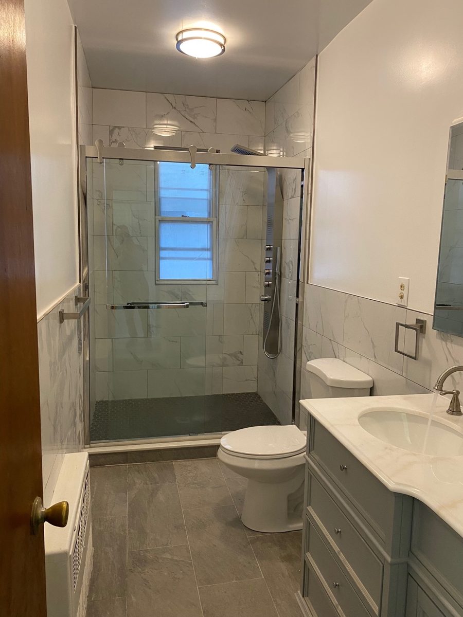 Same bathroom after: walk-in shower with a glass door